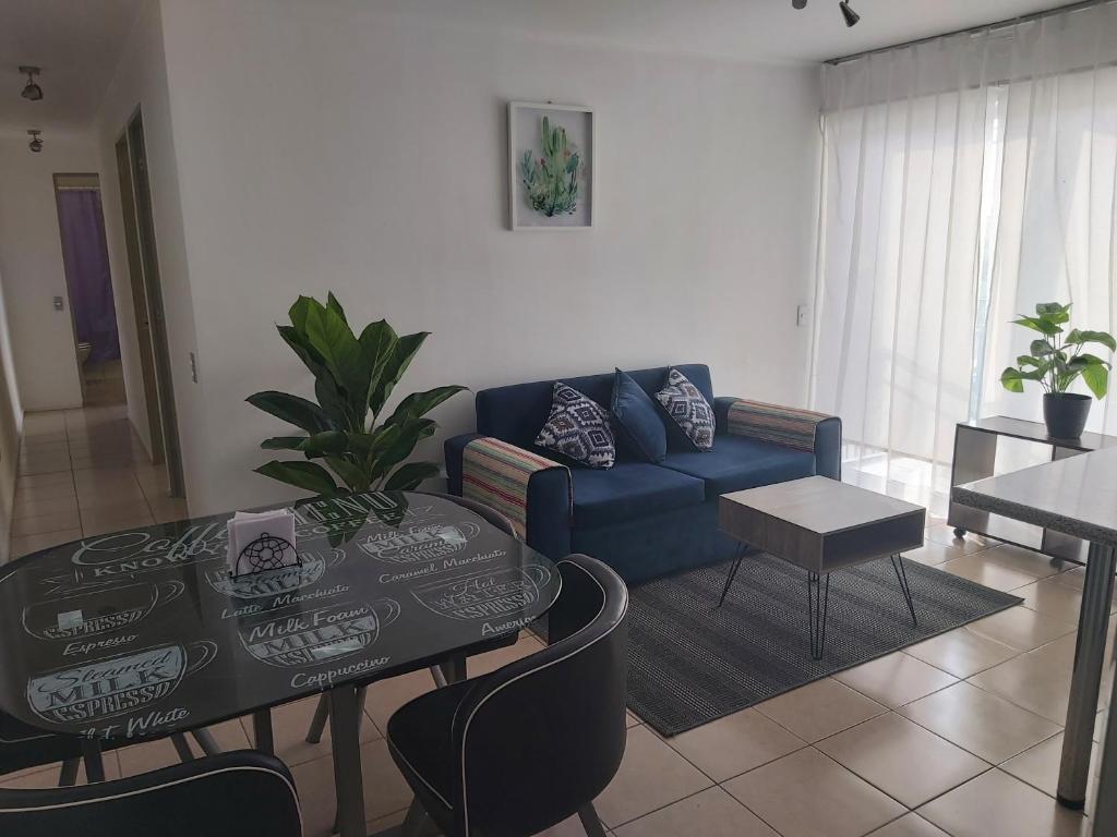 a living room with a blue couch and a table at Departamento Amoblado 3322 in Mejillones