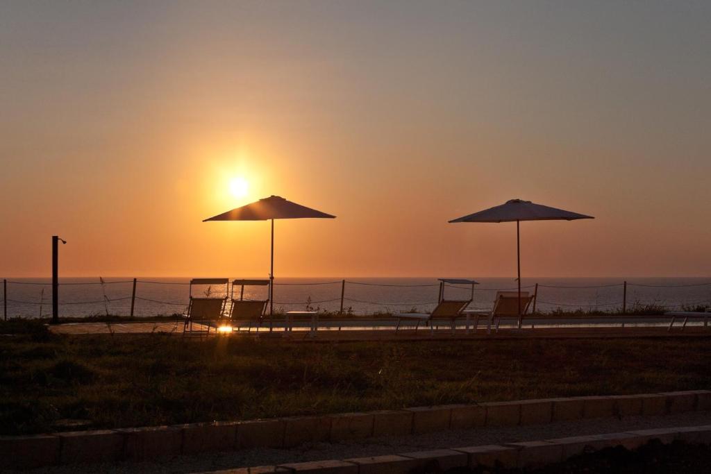 two chairs and umbrellas on the beach at sunset at Casa Vacanza Casa nel Sole in Siracusa