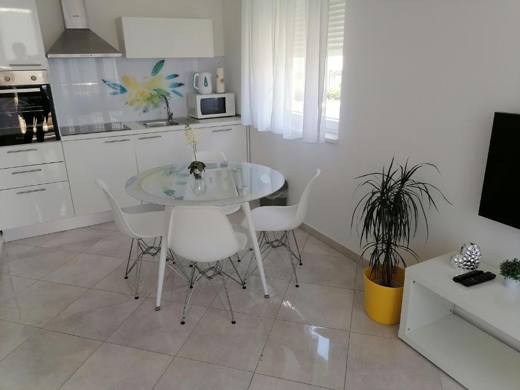 une cuisine avec une table en verre et des chaises blanches dans l'établissement Sweet Apartments, à Split