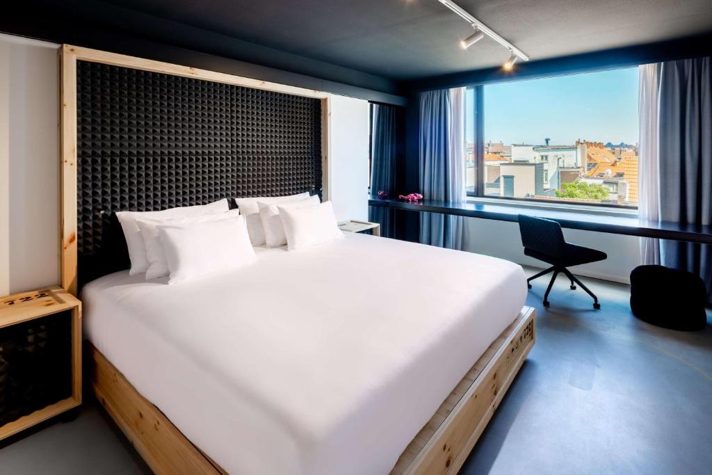 
a hotel room with a large bed and a large window at nhow Brussels Bloom in Brussels
