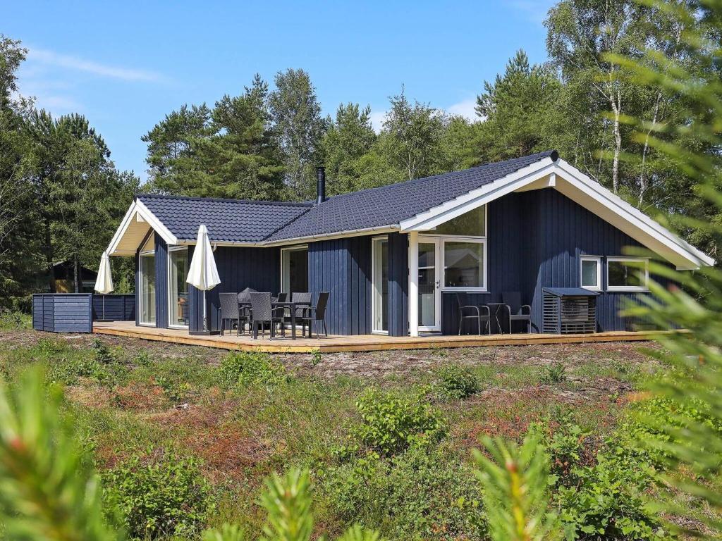 a blue cottage with a deck and patio at 8 person holiday home in L s in Læsø