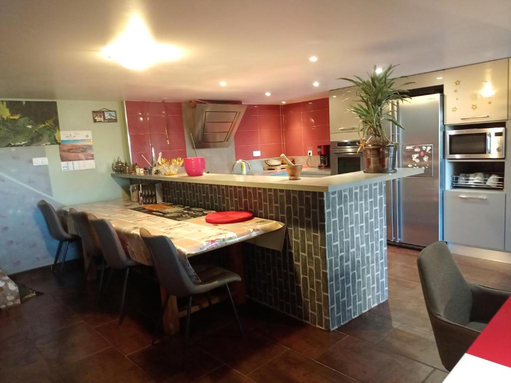 une cuisine avec des placards rouges et une table avec des chaises dans l'établissement Maison de campagne tout confort, bol d'air frais, à Saint-Beauzély
