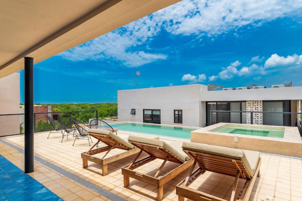 a patio with chairs and a swimming pool at Sessile Tulum by The Spot Rentals in Tulum