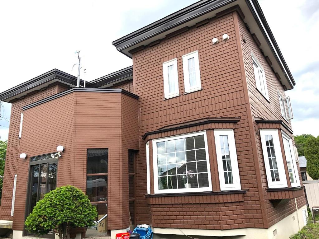 a brown brick house with white windows on a street at Chitose Guest House Oukaen in Chitose