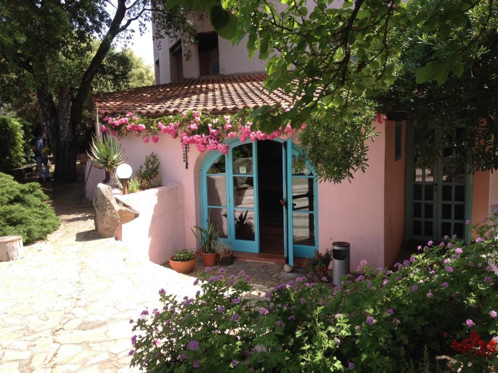 a pink house with a blue door and flowers at Hotel Scintilla in San Teodoro