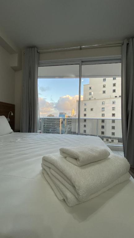 een slaapkamer met een wit bed en een groot raam bij Flat de luxo centro SP com piscina,academia,lavanderia,garagem e segurança 24h in Sao Paulo