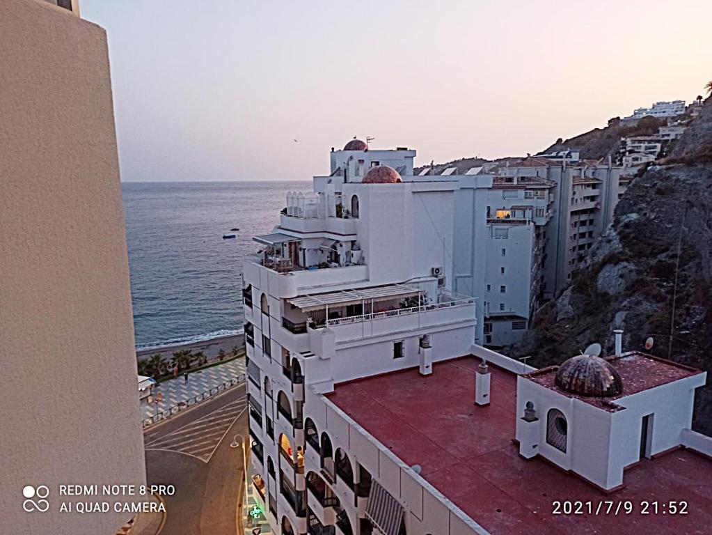 a building on the side of a cliff next to the ocean at Apartamentos Sol y Playa Almuñecar 2 in Almuñécar