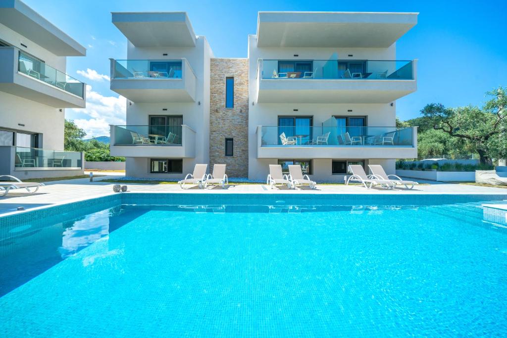 a villa with a swimming pool in front of a building at Aquamarine Luxury Rooms Thassos in Limenas