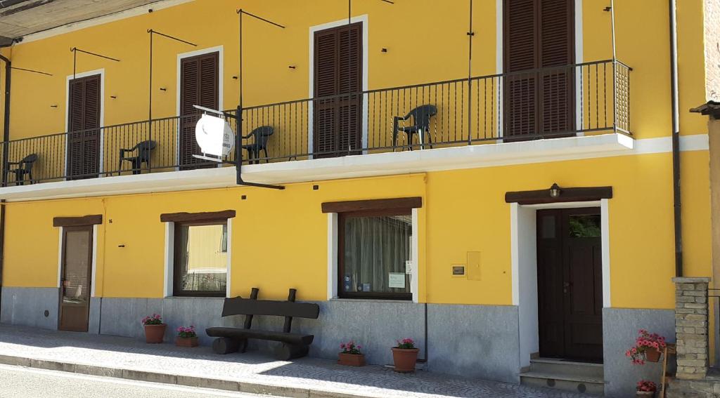 a yellow building with a bench in front of it at Affitta Camere La Dolce Sosta in Perosa Argentina