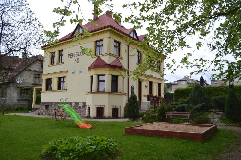 una casa con un parque infantil delante de ella en Pension65, en Police nad Metují