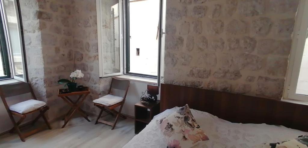 um quarto com uma cama, 2 cadeiras e janelas em Simply Dubrovnik em Dubrovnik