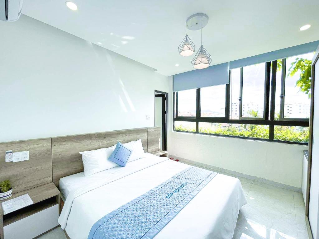a bedroom with a large white bed and windows at Bap Homestay in Hoi An