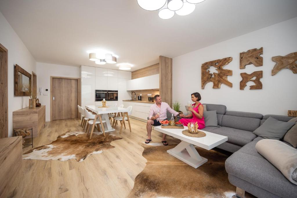 a man and woman sitting on a couch in a living room at Apartmány Kaskády Luhačovice in Luhačovice