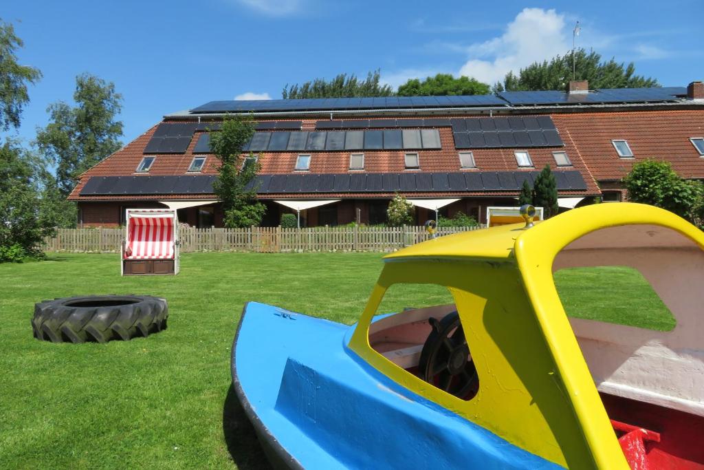 a playground in front of a building with solar panels at Ferienanlage Achtern Diek in Thalingburen