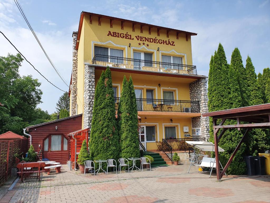 um edifício com mesas e cadeiras em frente em Abigél Vendégház em Miskolctapolca