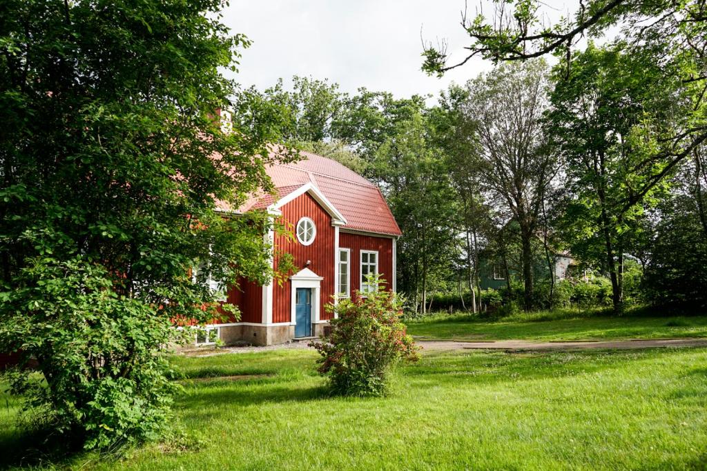 eine rote Scheune mit einer weißen Tür im Gras in der Unterkunft Nordic Refuge B&B in Fröskog