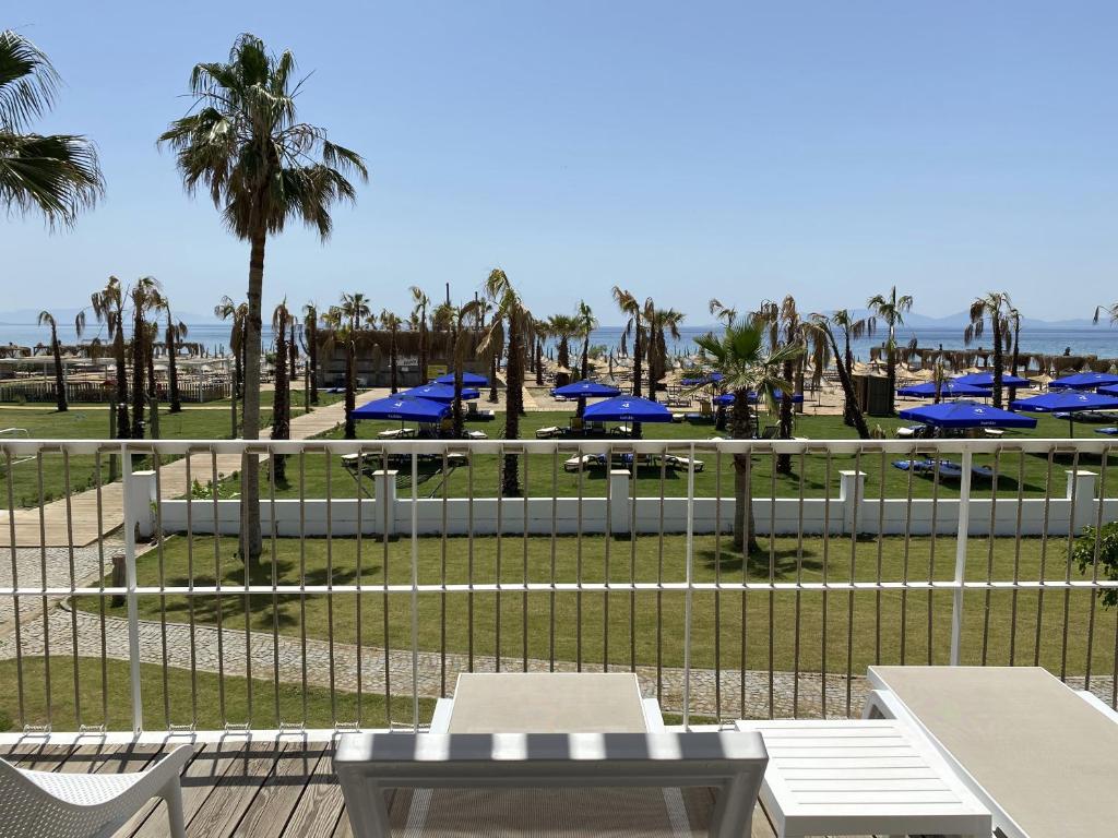 a view of a beach with picnic tables and palm trees at Ayvalık Sea Resort in Ayvalık