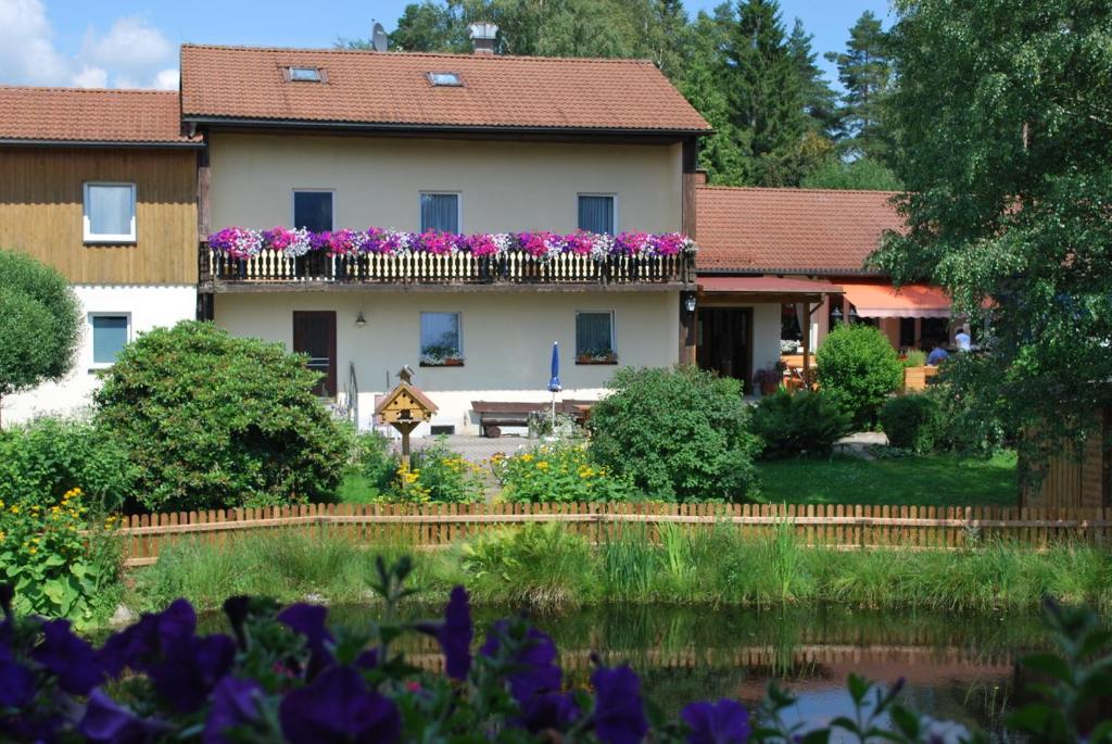 une maison avec des fleurs violettes sur un balcon dans l'établissement Wirtshaus Birkenhof, à Weißenstadt