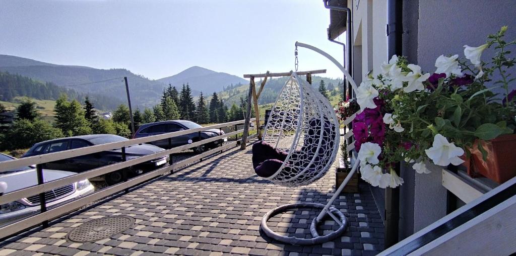 a patio with a swing and flowers on a balcony at Приватна садиба Соломія in Bukovel