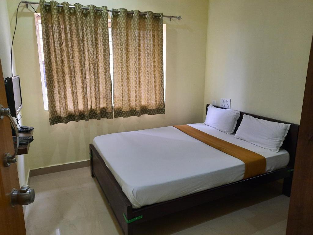1 dormitorio con 1 cama grande y ventana en Royal Suvarna Comforts, en Mysore