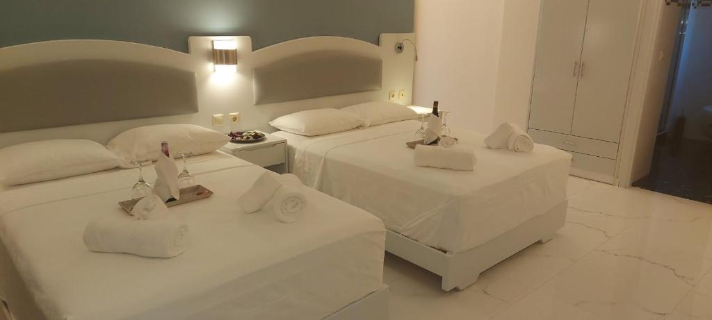 a bedroom with two beds with white sheets at Augusta Methoni Hotel in Methoni