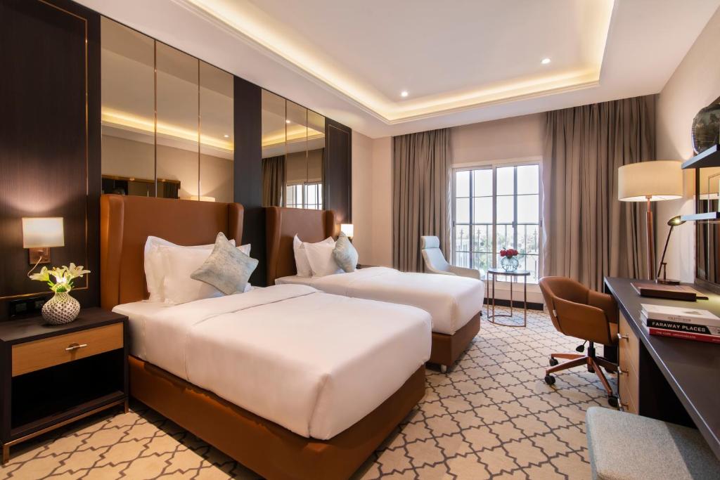 a hotel room with two beds and a desk at Gardino Hotel & Residence in Riyadh