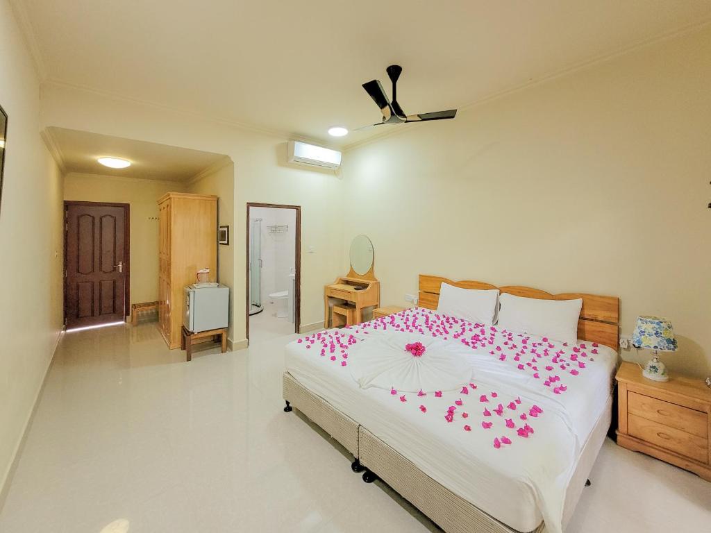 - une chambre avec un grand lit orné de fleurs roses dans l'établissement Sunrise Inn, à Thoddoo