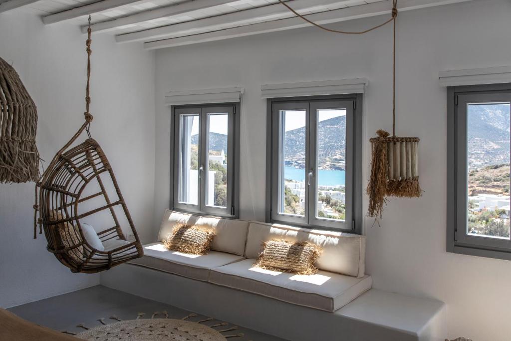 Nesea Sifnos - Luxury Residences في بلاتيس ييالوس سيفنوس: غرفة بها ثلاث نوافذ ومقعد به أضواء
