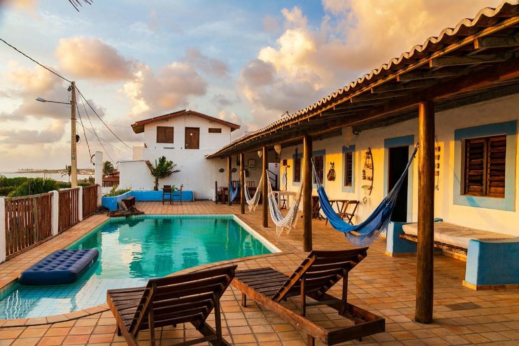 a swimming pool with two chairs and a house at Pousada Casa Feliz Maxaranguape in Maxaranguape
