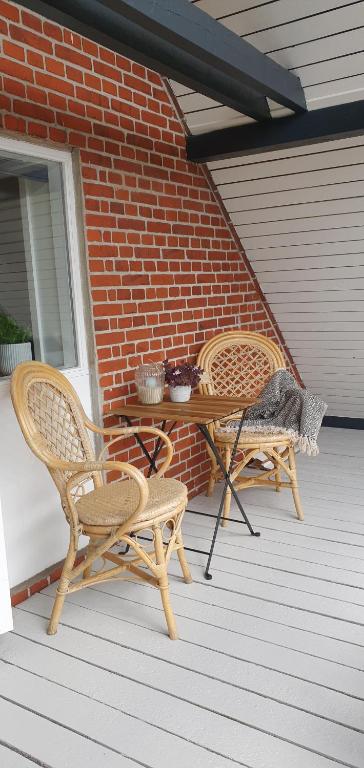 2 Korbstühle und ein Tisch auf einer Veranda in der Unterkunft Jyllandsgade B&B in Grindsted