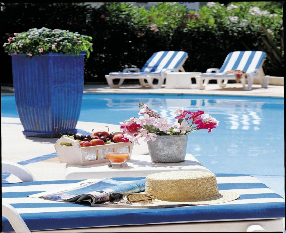 a table with a bowl of fruit next to a swimming pool at Hôtel Les Rives Bleues in La Grande Motte