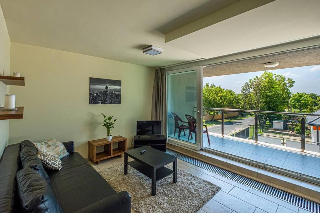 a living room with a couch and a large window at Hedon Brewing Balatonvilágosi apartment - 200 meter to the Beach in Balatonvilágos