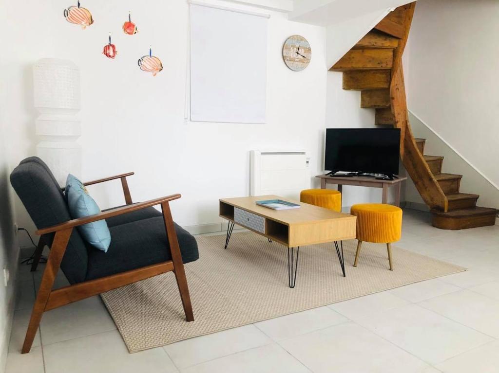 ein Wohnzimmer mit einem Stuhl, einem Tisch und einem TV in der Unterkunft Maison de ville, 2ch, La Petite Aure in Bayeux