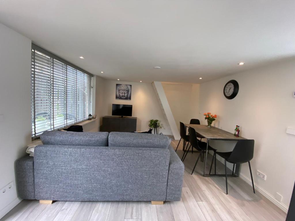 - un salon avec un canapé bleu et une table dans l'établissement Cozy Tiny House Egmond aan Zee- 500m from Beach-North Sea, à Egmond aan Zee