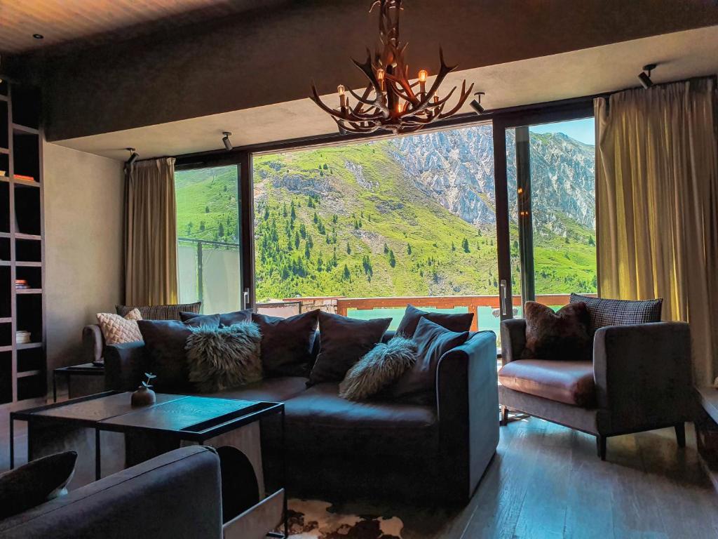 a living room with a couch and a large window at Langley Hôtel Tignes 2100 in Tignes
