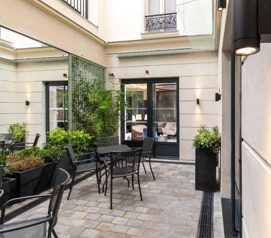 a patio with a table and chairs and plants at Hotel Montfleuri Champs-Elysées in Paris