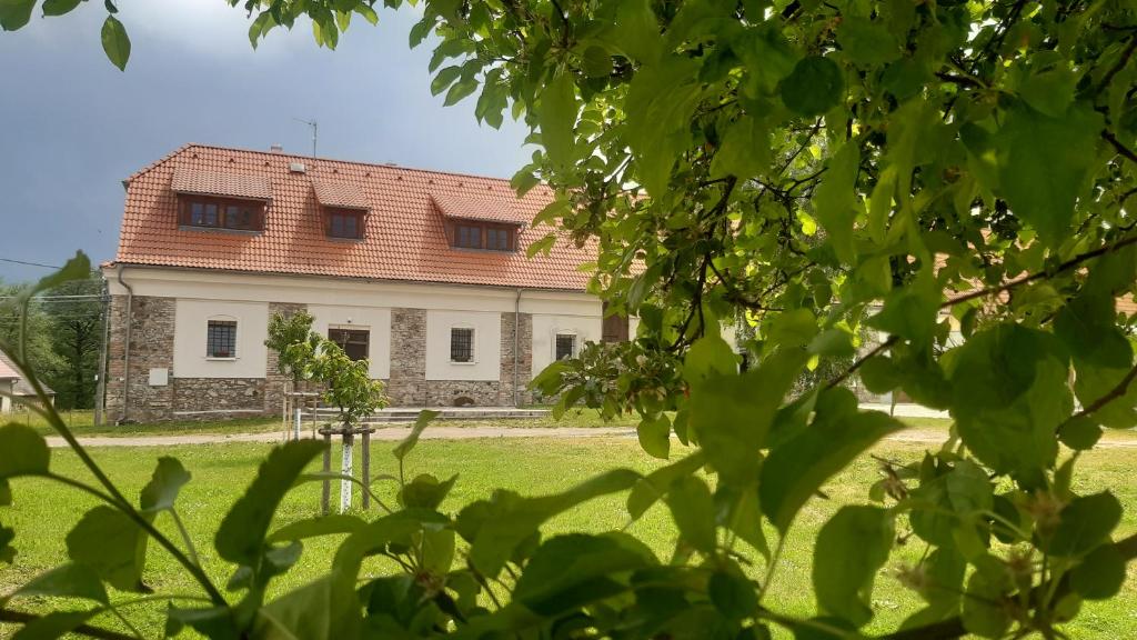 a white house with a red roof in a yard at Korn-Hof in Kornatice