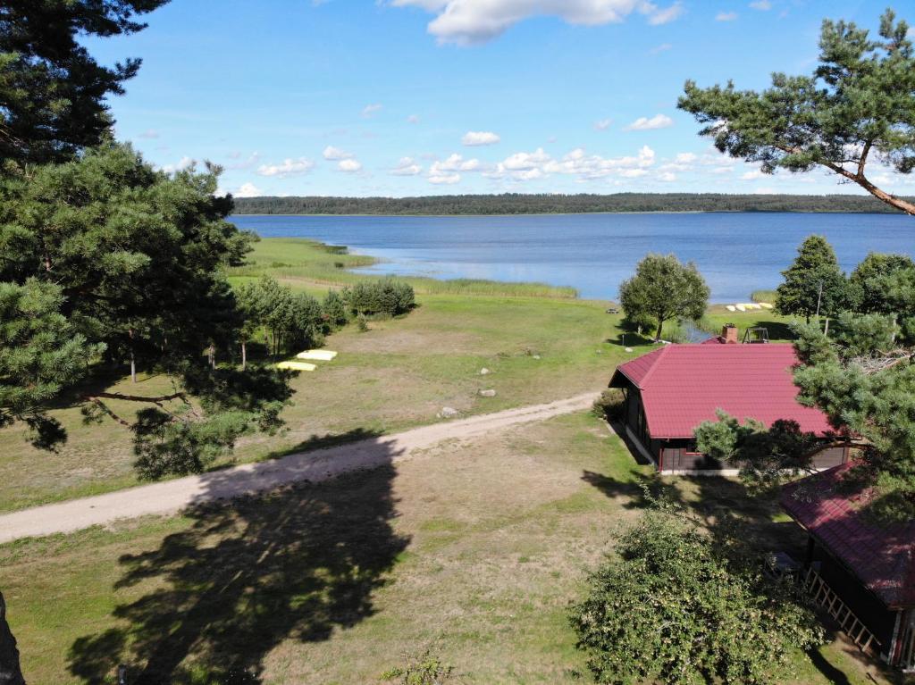 einen Blick über eine rote überdachte Scheune neben einem See in der Unterkunft Brīvdienu māja Greiži in Dzirciems