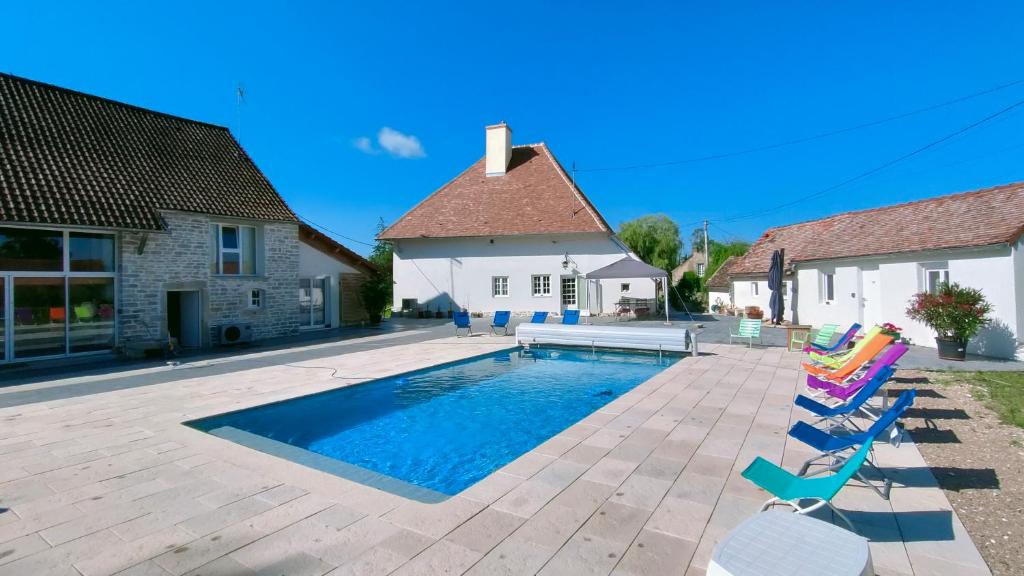 a swimming pool with chairs and a house at Domaine Ravy-Lilas in Saint-Symphorien-sur-Saône