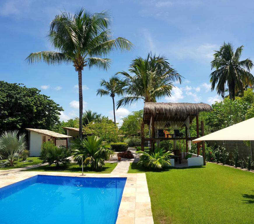 a villa with a swimming pool and palm trees at Pousada Villages Boutique Hotel - 150m da Praia da Laje in Pôrto de Pedras