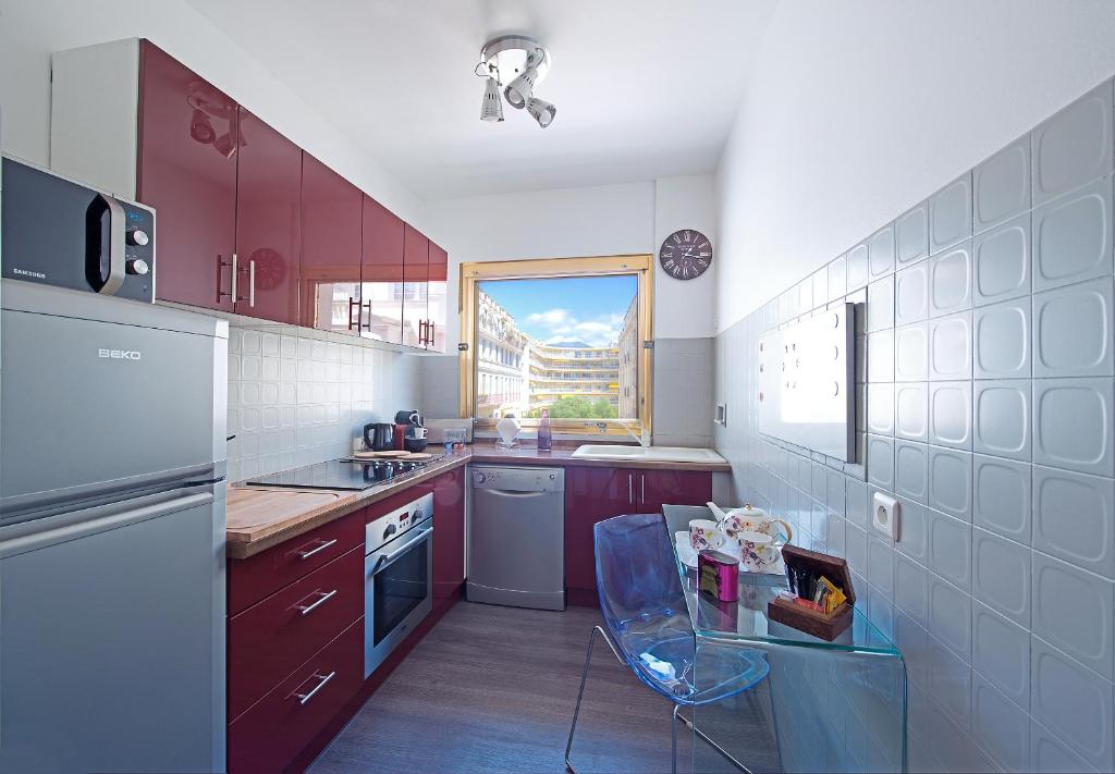 a small kitchen with red cabinets and a window at Appartement Rue Grimaldi in Nice