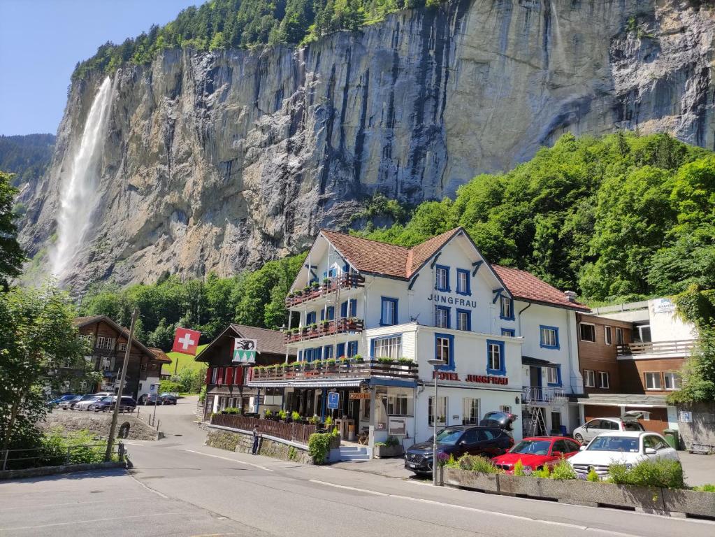 a building in front of a mountain with a waterfall at Hotel Restaurant Jungfrau in Lauterbrunnen