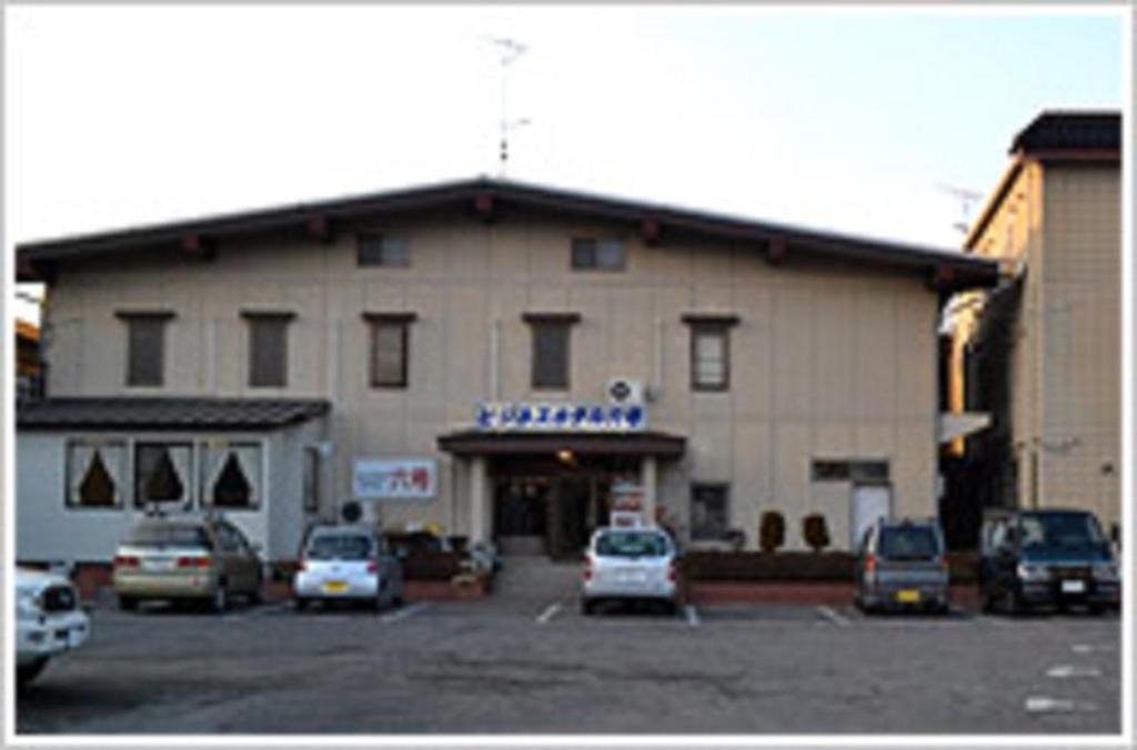 a large building with cars parked in a parking lot at ビジネスホテル六号 in Omitama