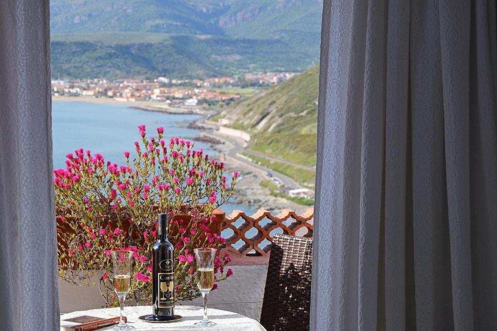 einen Tisch mit Weingläsern und Blumen auf dem Balkon in der Unterkunft Hotel Sa Lumenera in Bosa