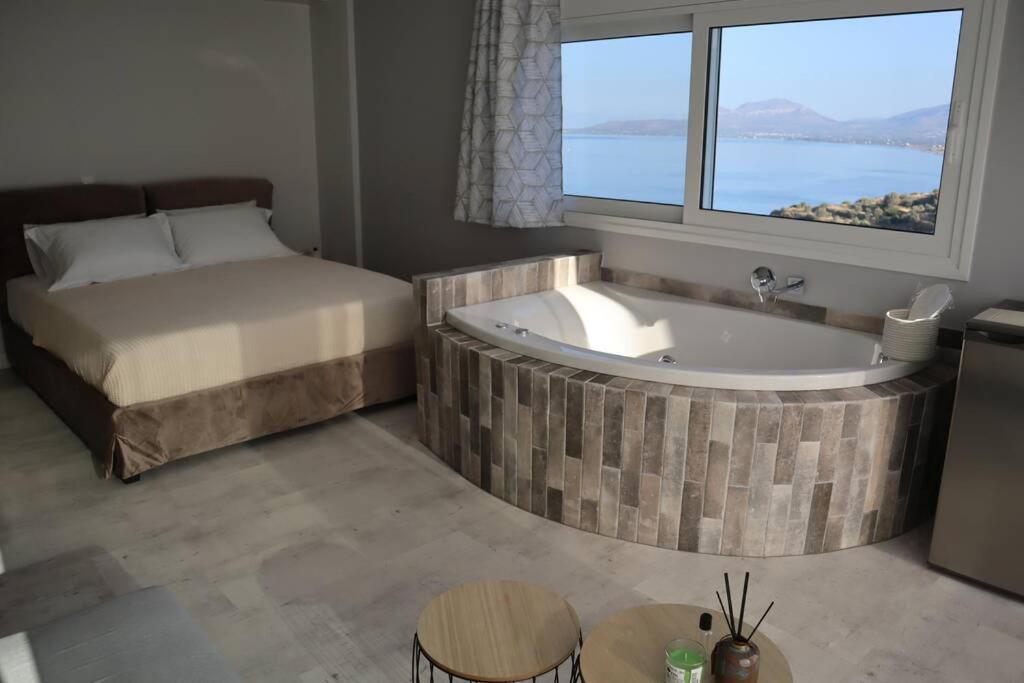 a bedroom with a tub and a bed and a window at 360° View Suites Tan in Neapolis