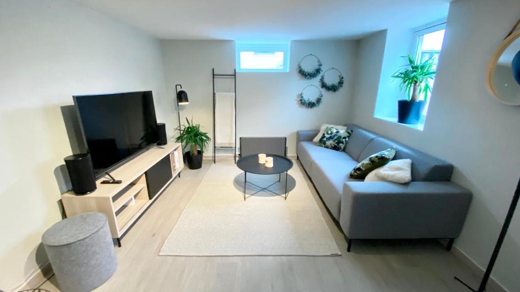 uma sala de estar com um sofá azul e uma televisão em Two bedroom apartment near the city centre. em Tromsø