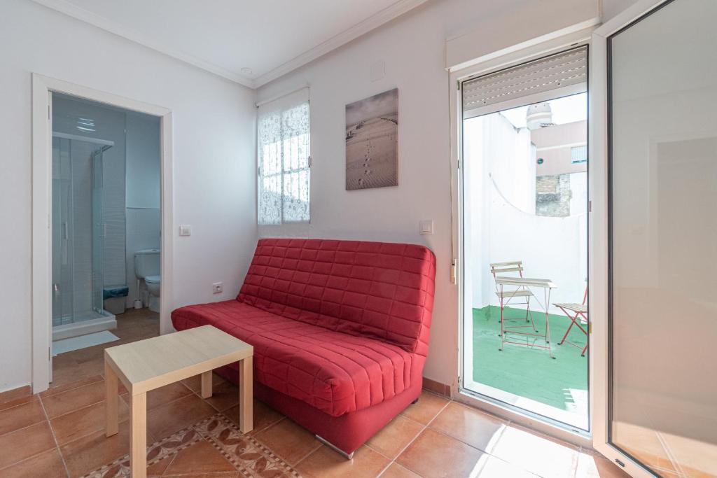 een rode bank in een woonkamer met een tafel bij Apartment La Gitanilla terrace in Cádiz