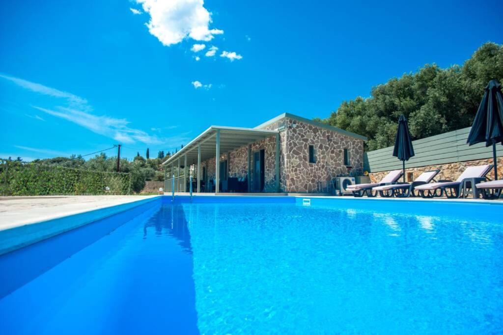 a swimming pool with blue water in front of a building at Villa Afrato Calma in Trapezaki-private pool -2 BR in Trapezaki
