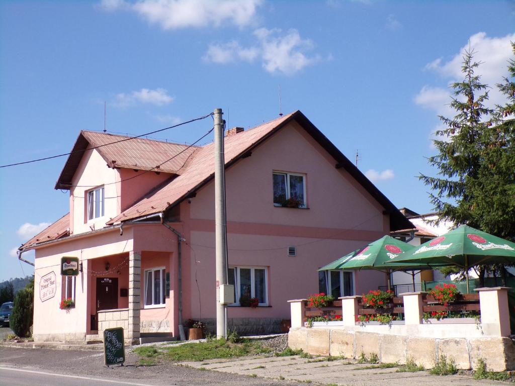 różowy budynek z zielonymi parasolami przed nim w obiekcie U Křemílka w Jiczynie