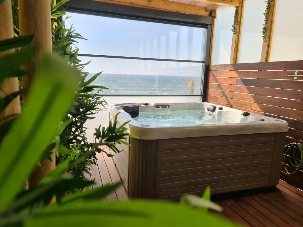 bañera de hidromasaje en una habitación con ventana grande en GOLD SUITE T2-PRAIA DO FURADOURO, en Ovar